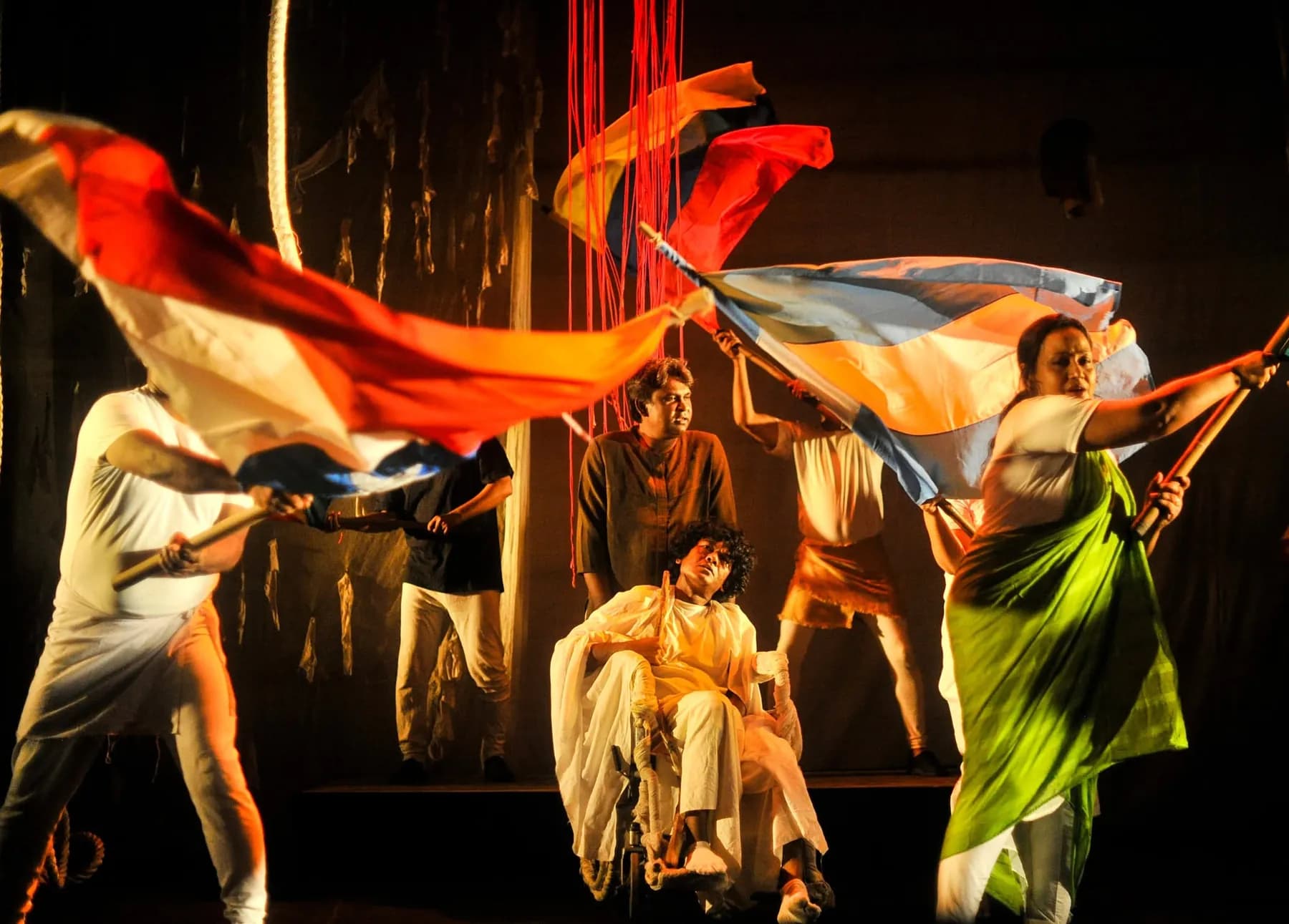 Performers sweeping coloured flags across a stage