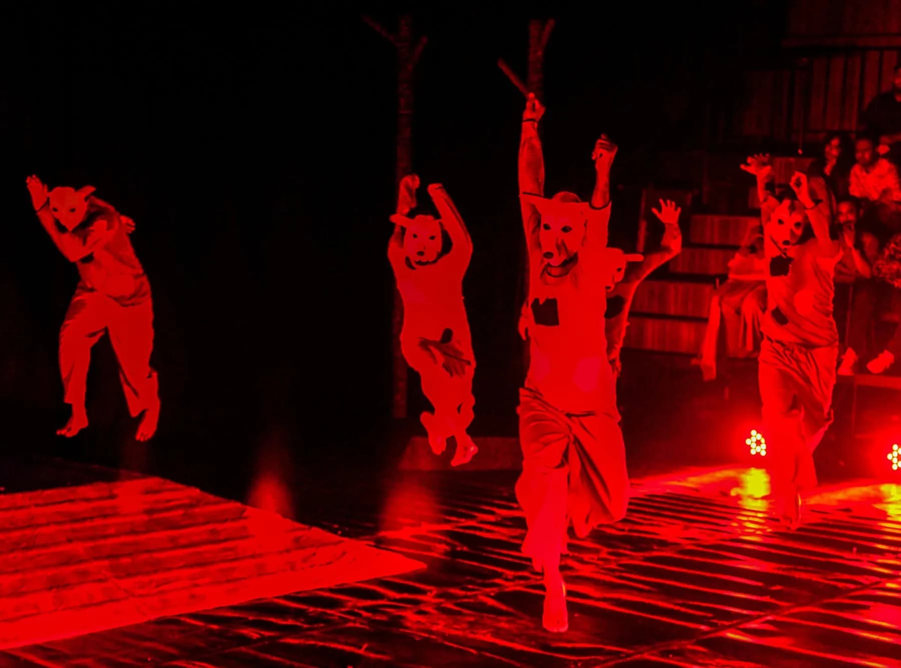 Dancers leaping across a stage washed in red